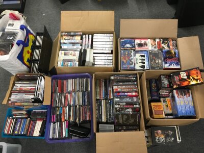 A collection of CDs, DVDs and VHS tapes.