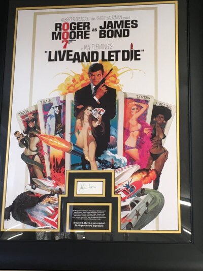 James Bond Live And Let Die. A framed and signed poster display with the signature of Roger Moore with COA, approx 76cm x 96cm including frame.