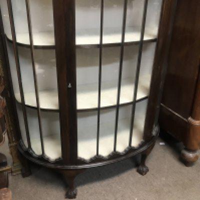 A mahogany semi circular display cabinet on ball and claw feet. NO RESERVE