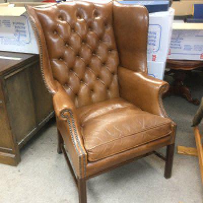A leather button back wing armchair. Shipping category D.