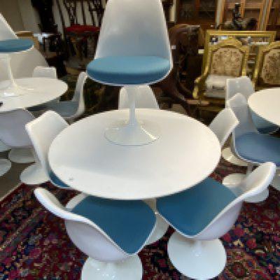 Mid Century Tulip dining suite (Table and 6 chairs) designed by Eero Saarinen 1956 (Finnish-American, 1910-1961) for Knoll, laminated top over a curved painted metal base, stamped 'Knoll Studio', 107cm diameter 73cm high, and six 'Tulip' chairs, each with a white plastic shell over a painted metal base. (Mixed Light blue / turquoise blue upholstered cushions).