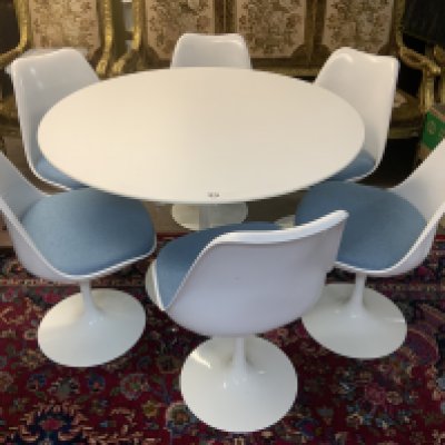 Mid Century Tulip dining suite (Table and 6 chairs) designed by Eero Saarinen 1956 (Finnish-American, 1910-1961) for Knoll, laminated top over a curved painted metal base, with label 'Knoll Studio', 107cm diameter 73cm high, and six 'Tulip' chairs, each with a white plastic shell over a painted metal base. (Light blue upholstered cushions).