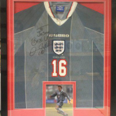 A framed and glazed 1998 England away shirt signed by David Beckham, approx 73cm x 98cm. Shipping category D.