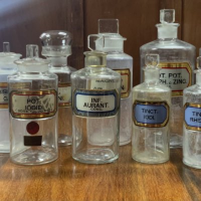 A collection early 20th century apothecary bottles and stoppers, each of cylindrical form with assorted faceted rectangular stopper and recessed labels. 16-24cm