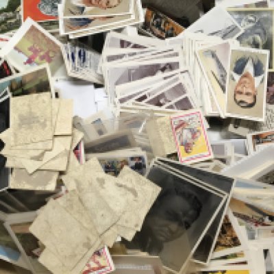 A box containing a collection of loose vintage cigarette cards and other cards.