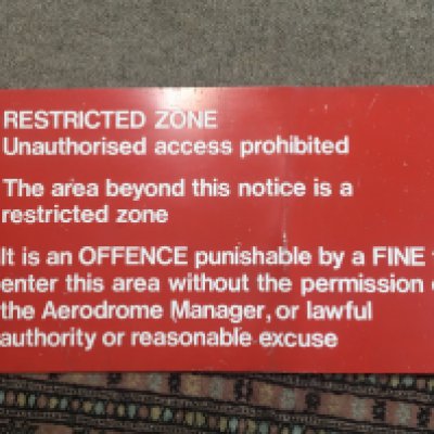 An Airport Restricted Zone sign 27cmx51cm red and white on aluminium.